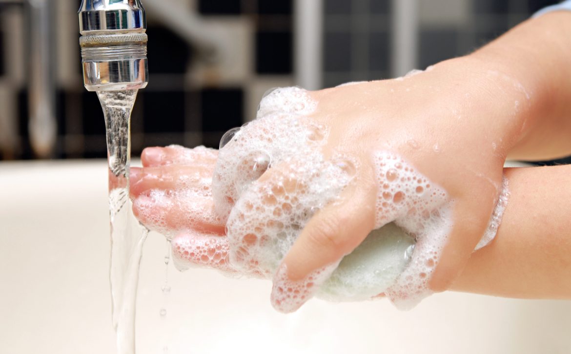 Close-up view of child scrubbing hands under faucet